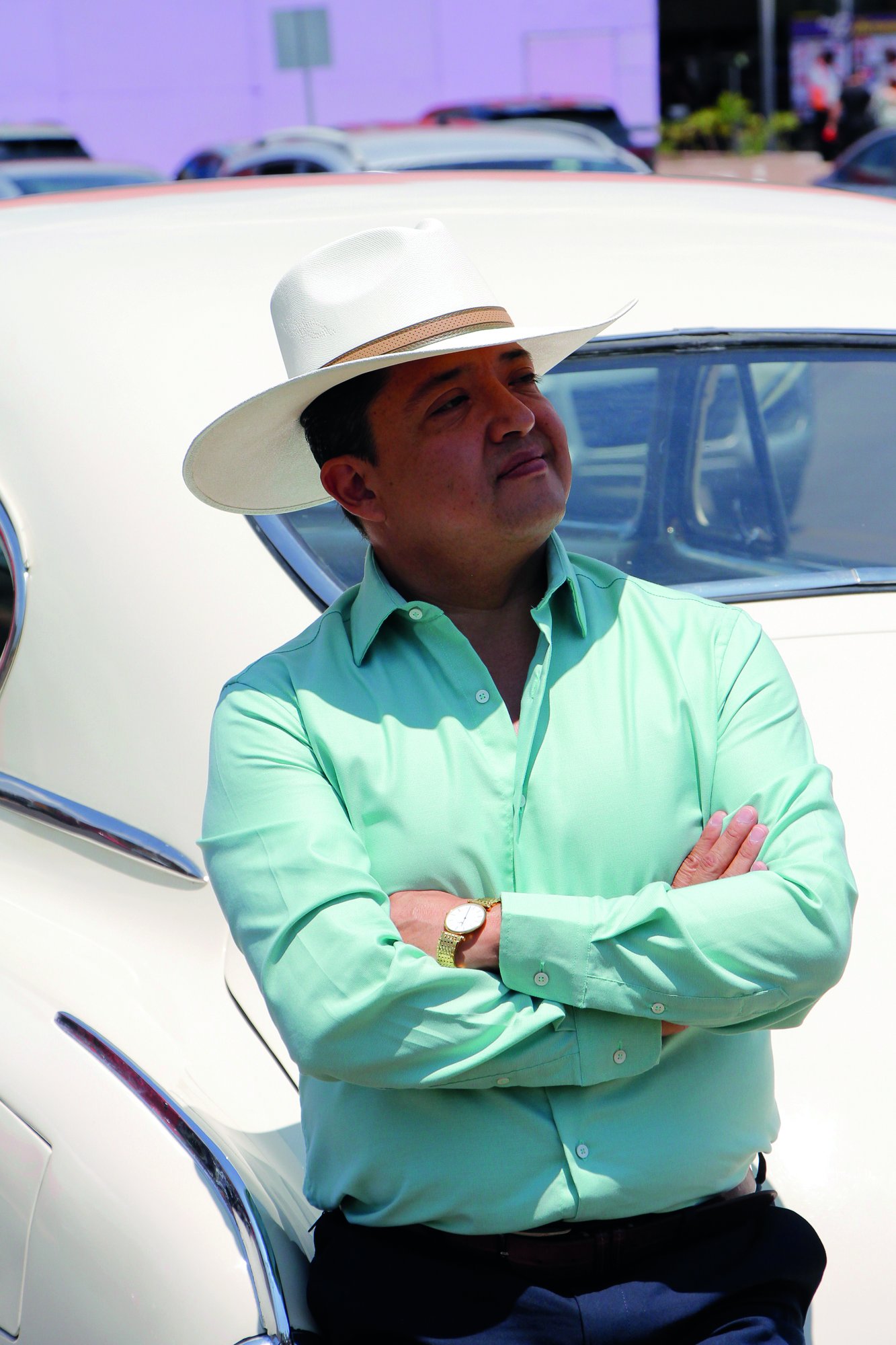 Emmanuel Rendón con sombrero junto a un auto clásico